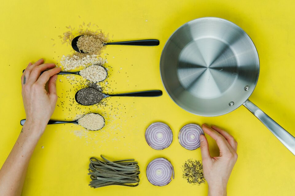 image showing various spices and ingredients on a yellow background next to a pan